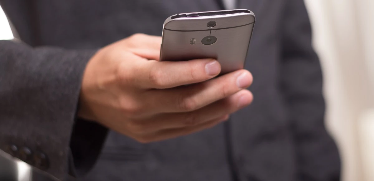 Foto de las manos de una persona con un smartphone gris.
