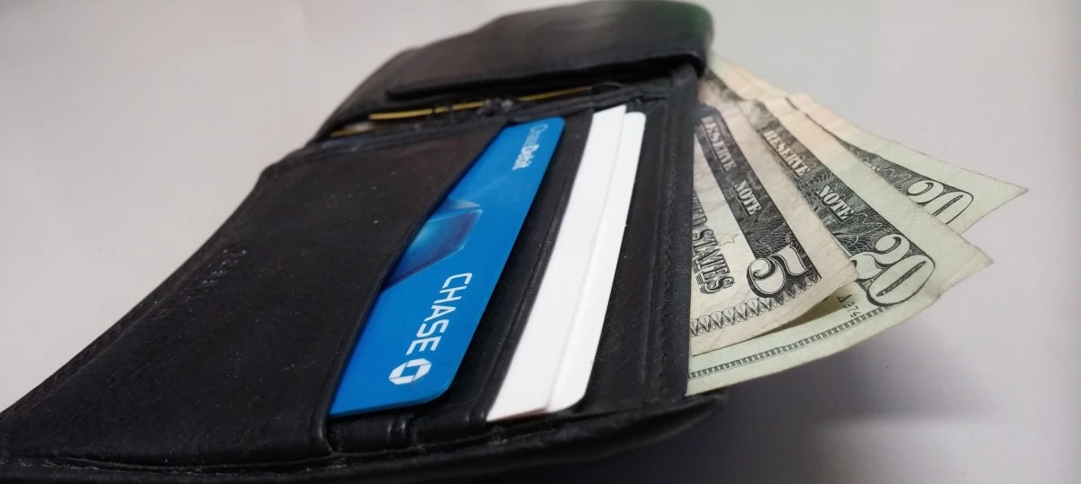 Billetera con una tarjeta de crédito azul y dólares.